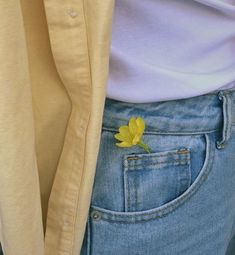 a yellow flower sticking out of the back pocket of someone's jeans