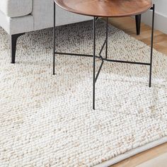 a living room with a couch, coffee table and rug on the floor in front of it