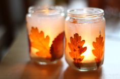 two glass jars filled with leaves on top of a table