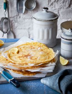 there are three pancakes on the table with lemons next to it and a canister