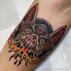 a tattoo on the arm of a man with an animal head and flames coming out of it