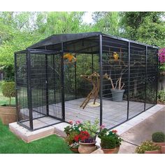 a large black caged in area with flowers and potted plants on the ground