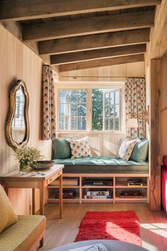 a living room filled with furniture next to a window covered in curtains and pillows on top of a wooden floor