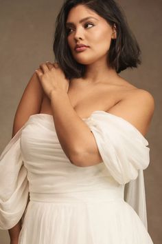 a woman in a white dress is posing for a photo with her hands on her chest