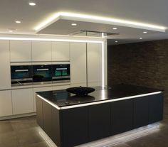 a large kitchen with white cabinets and black counter tops, along with an island in the middle