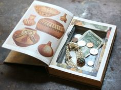 an open book with pictures and coins on the pages, sitting on top of a table