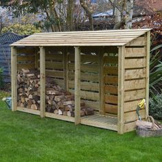 a wooden shed with logs stacked in the front and side by side on green grass