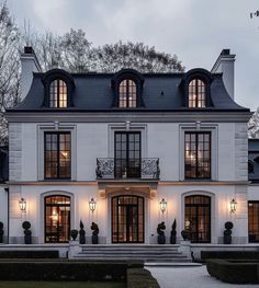 a large white house with lots of windows on the front and side of it at night