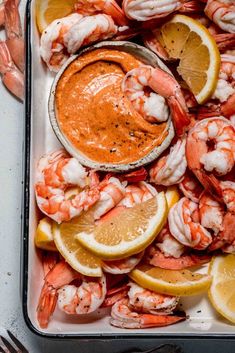 a tray filled with shrimp, lemons and sauce