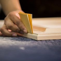 a person is holding a piece of wood on top of the floor with their hand