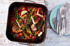 a pan filled with meat and vegetables on top of a blue plate next to a fork