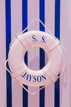 a life preserver hanging on a wall with blue and white striped walls behind it