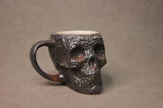 a coffee mug with a skull head on the inside is shown in front of a gray background