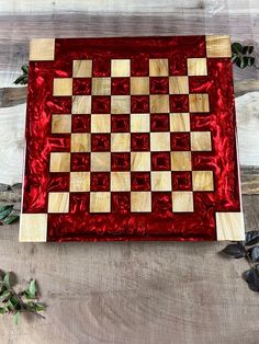 a red and white checkerboard board sitting on top of a wooden table next to leaves