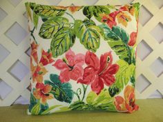 a pillow with flowers on it sitting on a green chair in front of a white wall