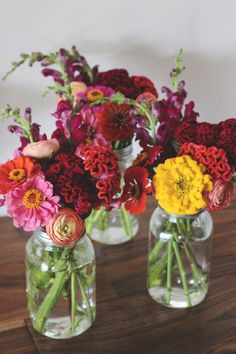 three vases filled with colorful flowers on top of a wooden table