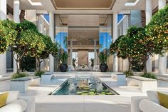 the lobby is decorated with potted trees and white couches, as well as a water feature