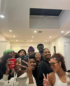 a group of people taking a selfie with their cell phones in a room full of white cabinets