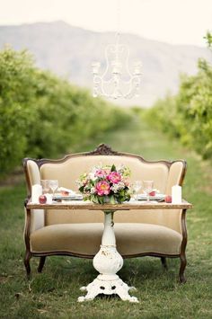 a table with flowers and candles on it in the middle of an apple orchard field