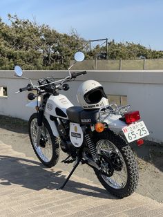 a motorcycle parked next to a white wall with a number plate on the front and side