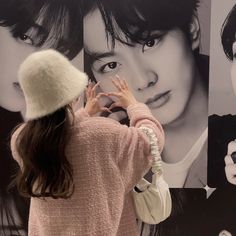 a woman standing in front of a wall with pictures on it's sides and her hands up to her face