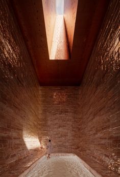 a person is standing in the middle of a room with brick walls and a skylight