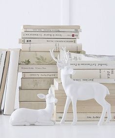 two white deer figurines sitting next to books