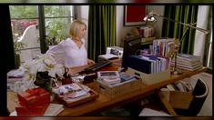 a woman sitting at a desk in front of a computer monitor and other office supplies