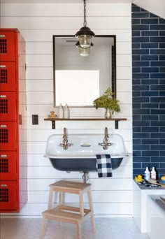 a white sink sitting under a mirror next to a red locker and wooden step stool