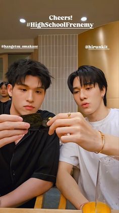 two young men sitting at a table eating food