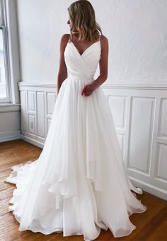 a woman in a white wedding dress standing on a wooden floor