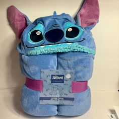 a stuffed animal that has been wrapped in a blue towel with pink ears and eyes