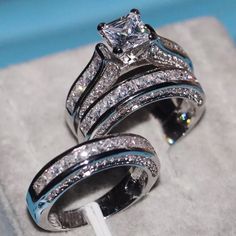 two wedding rings sitting on top of each other in a ring box, with diamonds surrounding them