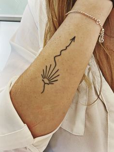 a woman's arm with an arrow tattoo on her left wrist and the word love written in black ink