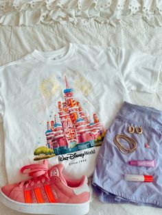 a pair of pink adidas sneakers next to a t - shirt with disney world on it