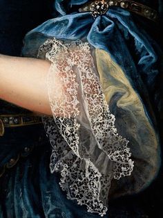 a painting of a woman's arm with white lace on it and a blue dress