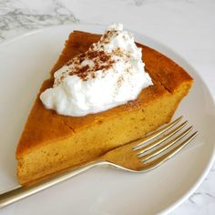 a piece of pumpkin pie with whipped cream on top and a fork sitting next to it