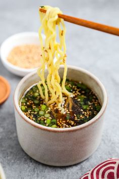 someone is eating noodles with chopsticks in a bowl