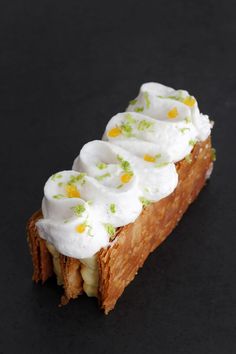 a piece of bread topped with whipped cream and other toppings on a black surface