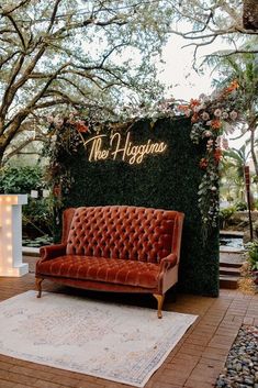 a couch sitting on top of a wooden floor next to a wall covered in plants