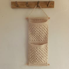 a crocheted bag hanging on a wall next to a coat rack with hooks