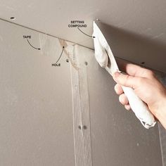 a person holding a cloth over the edge of a wall with tape and glue on it