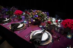 the table is set with plates, silverware and flowers