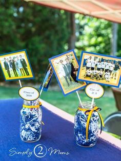 two mason jars with pictures on them are sitting on a blue table cloth under an awning