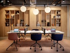 an office with two desks and three chairs in front of them, along with open shelving