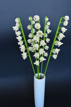 white flowers are in a blue vase on a black background