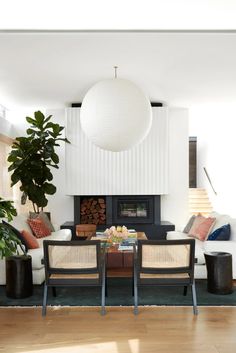 a living room filled with furniture and a fire place next to a plant on top of a hard wood floor