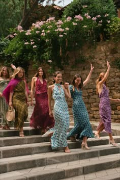 several women in dresses are walking down some steps and one woman is holding her arms up