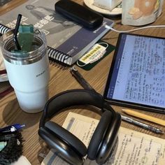 headphones and notebooks on a table next to a cup of coffee, cell phone