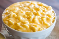 a white bowl filled with macaroni and cheese on top of a wooden table